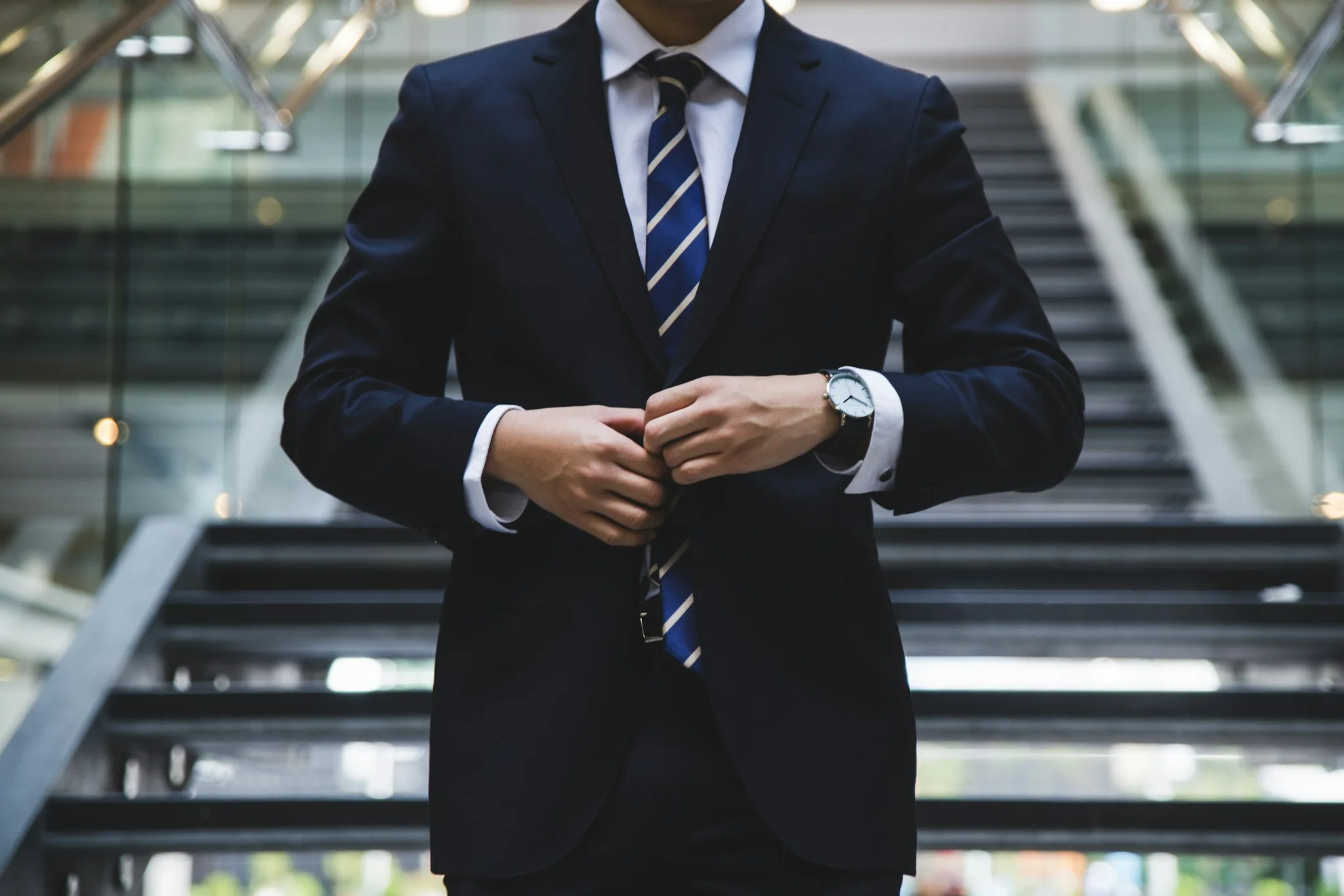 A man in a suit adjusting his tie on stairs.