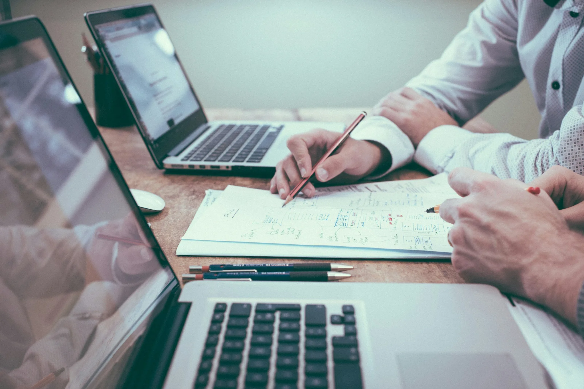 Two people collaborating over a document on a table.