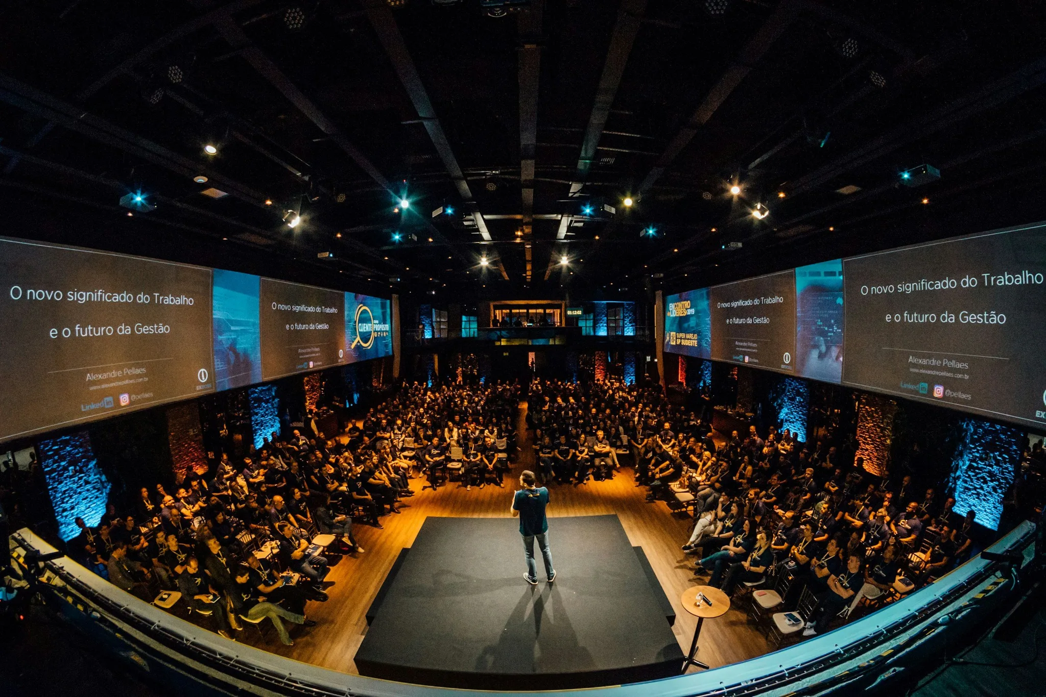 A presenter speaking to a large audience in a conference setting.