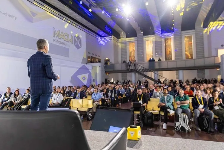 A speaker presenting to a large audience at a conference.