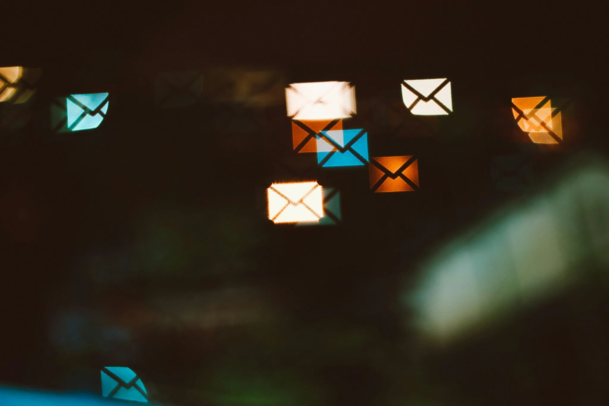 Colorful bokeh lights resembling envelopes on a dark background.