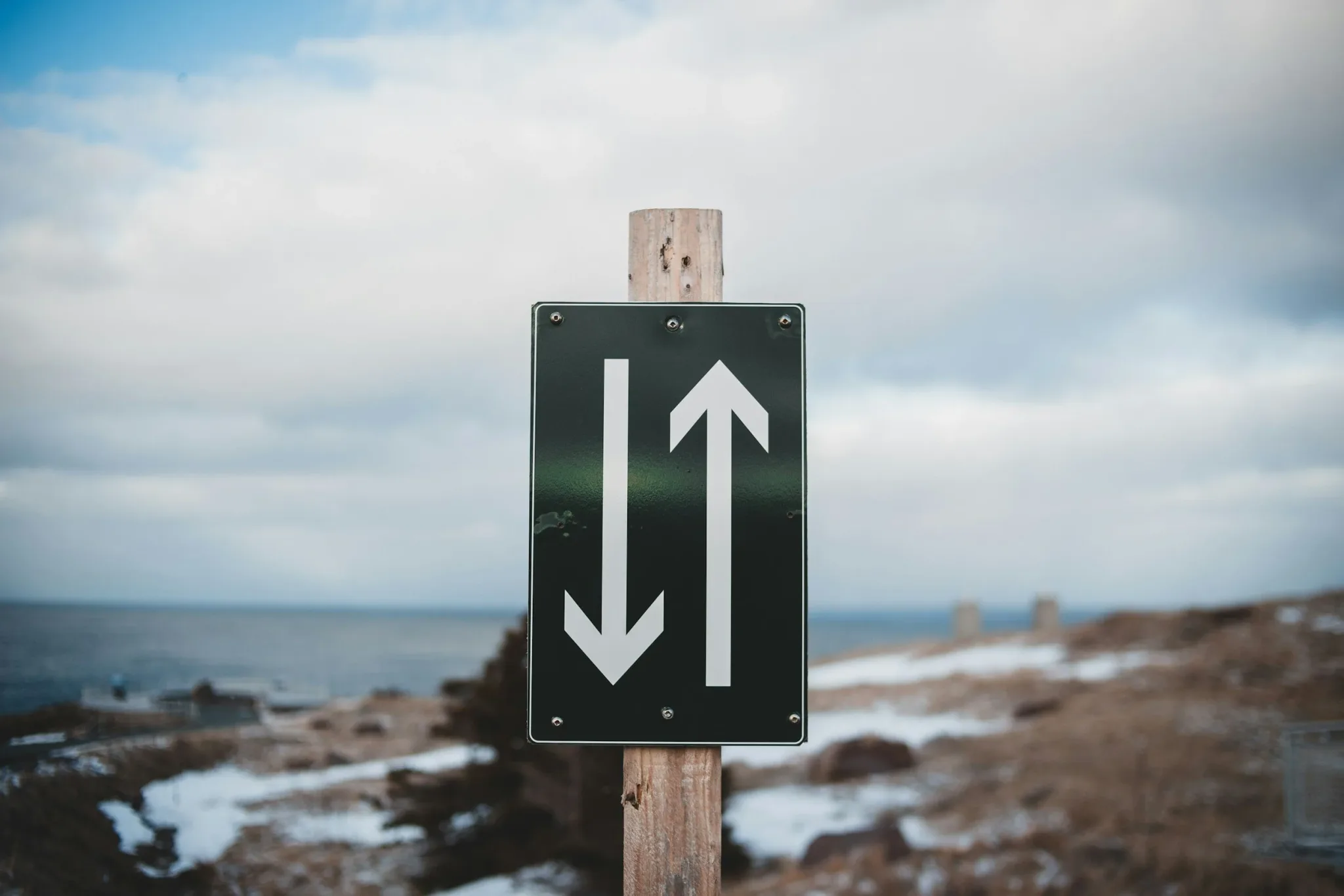 A traffic sign with opposing arrows near the coast.