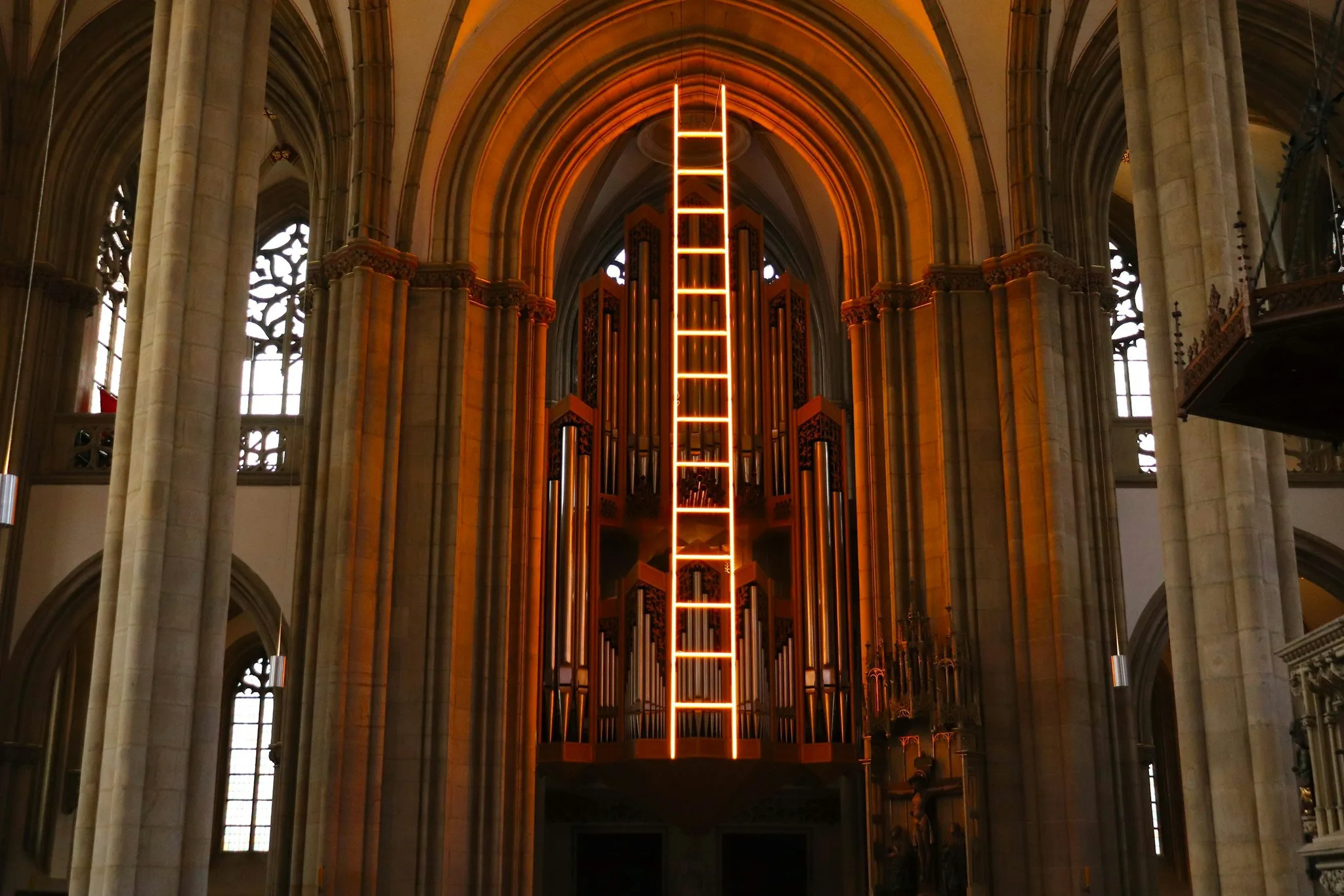 Interior of a cathedral with illuminated organ pipes.