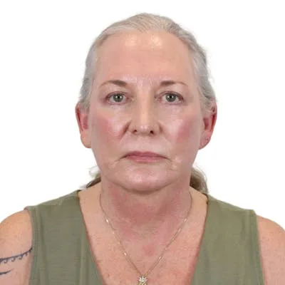 A woman with gray hair in a green top looking at the camera.