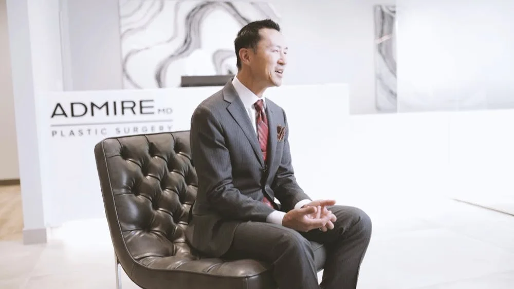 A man in a suit sitting in a modern clinic reception area.