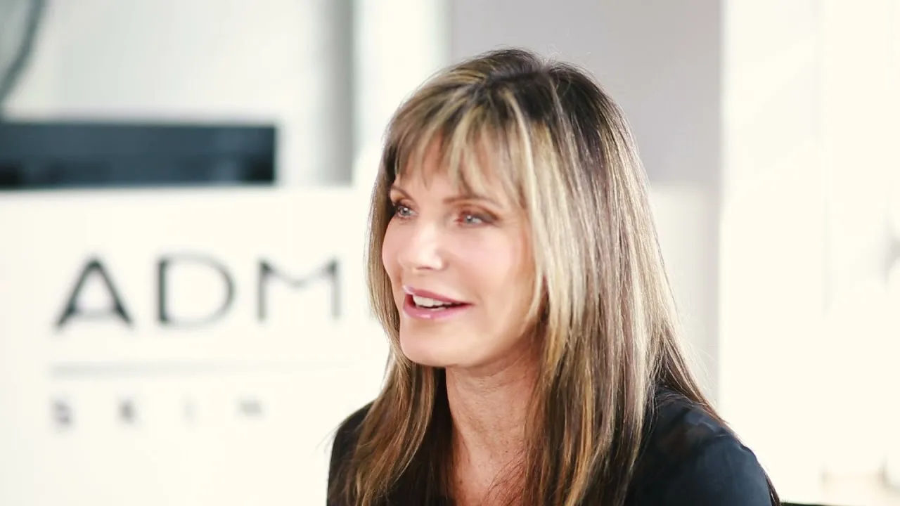 A woman smiling at AdmireMD Skin Clinic's interior.