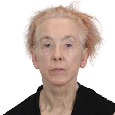 A mature woman with tousled hair and neutral expression.