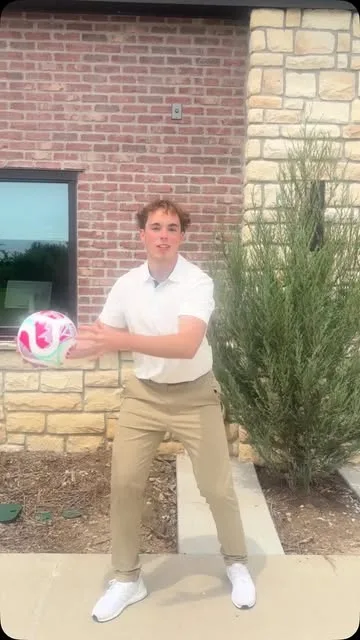 A young man holding a soccer ball outdoors.