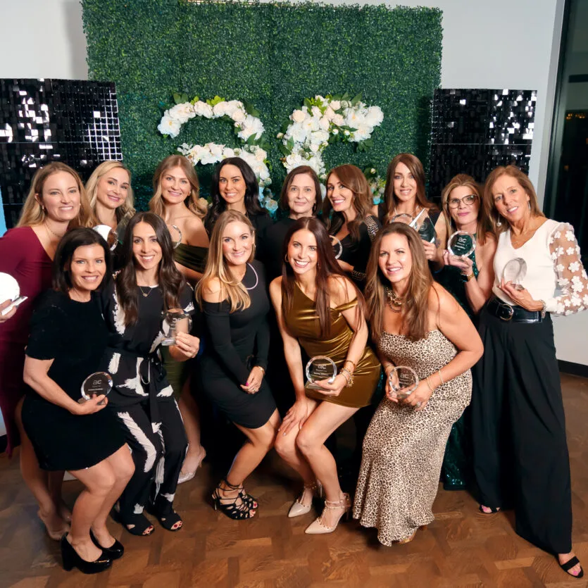 Group of women posing with awards at an event.