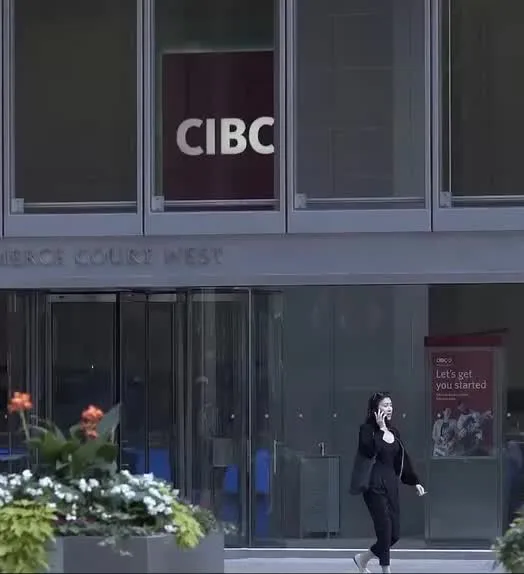 A woman in a black suit walking past a modern office building.