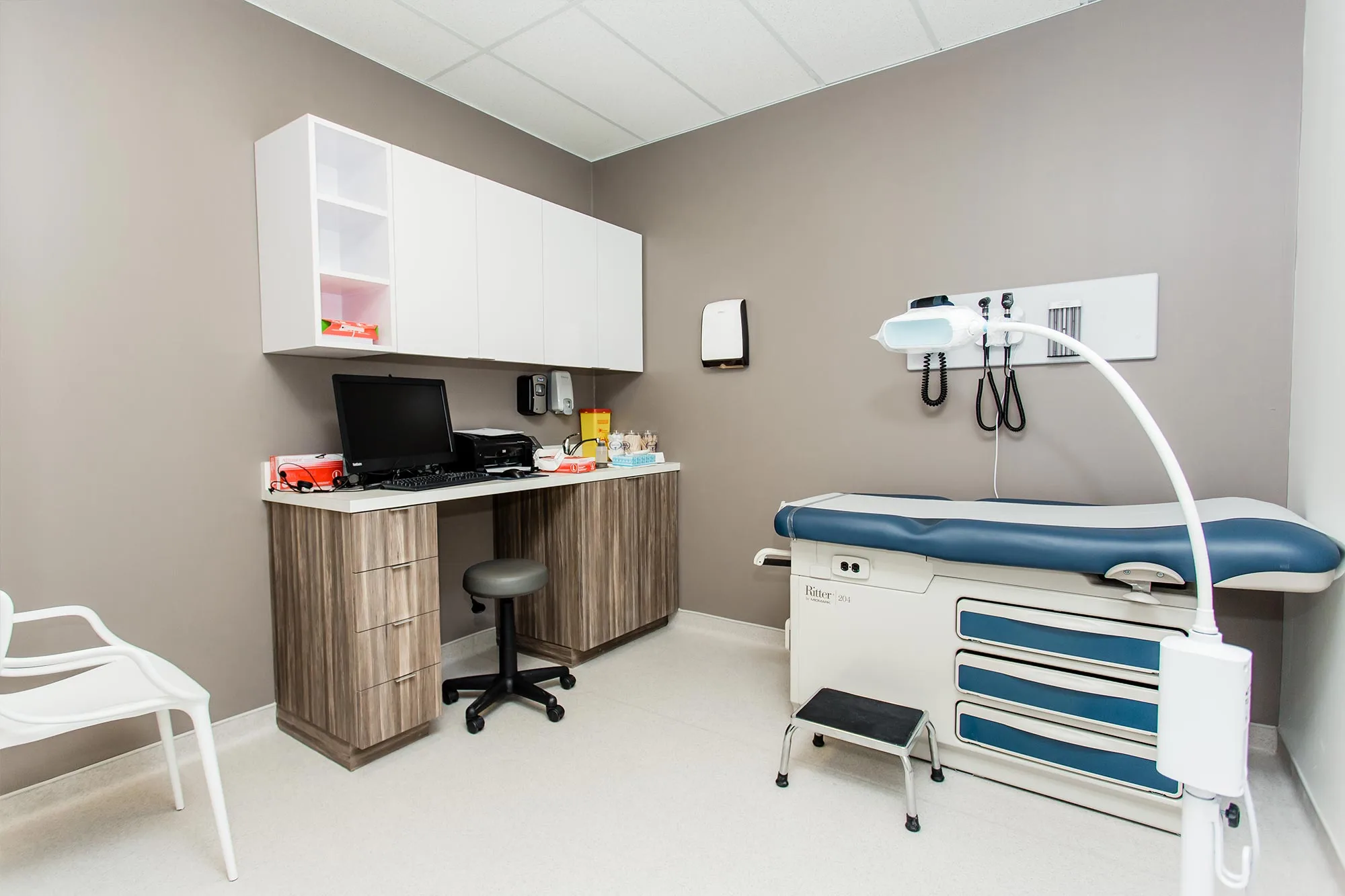 A medical examination room with a treatment table and desk.