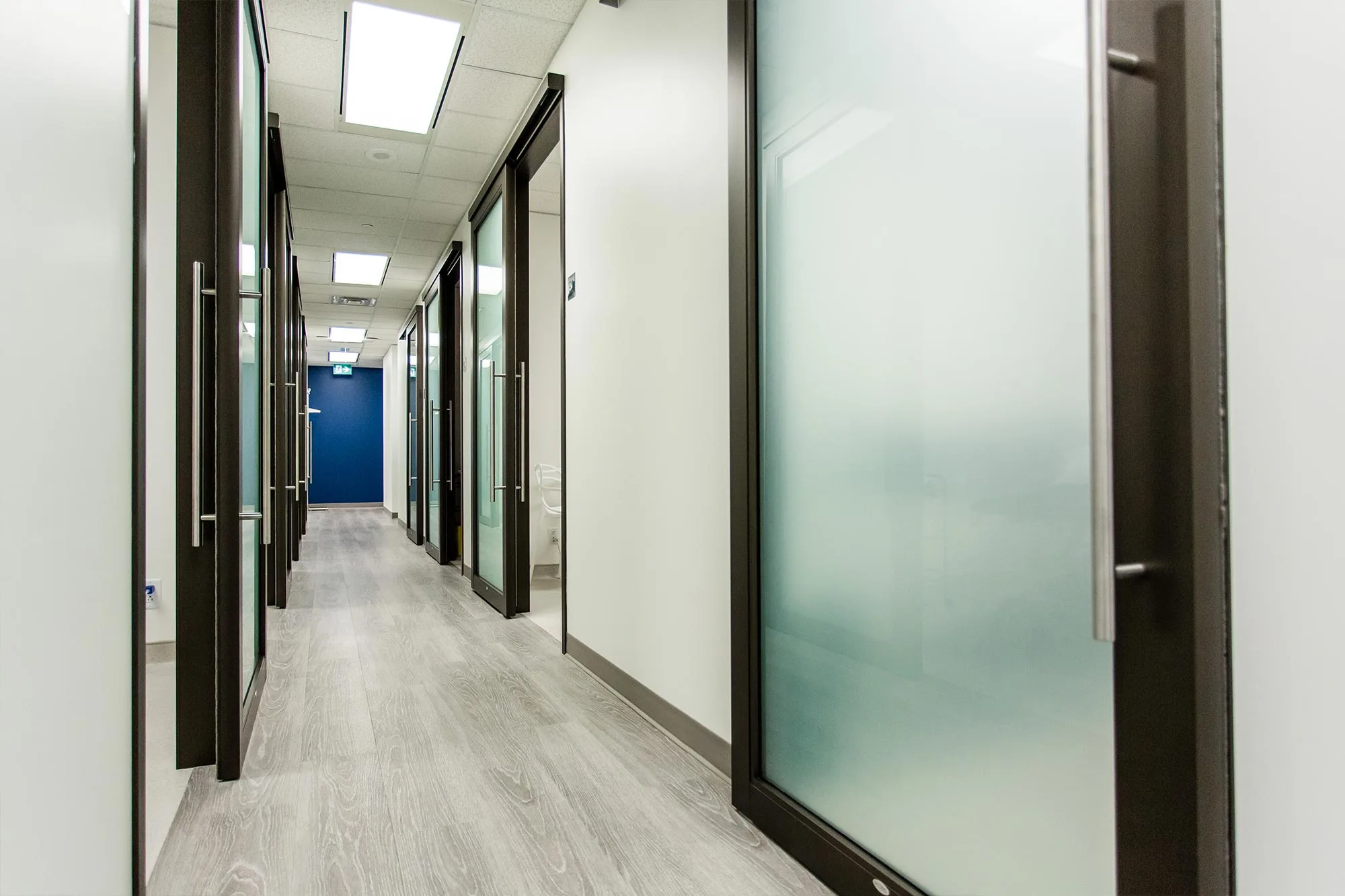 A clean and modern healthcare corridor with glass doors.