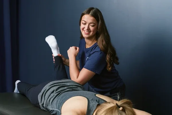 Therapist stretching a patient's leg in a clinic setting.