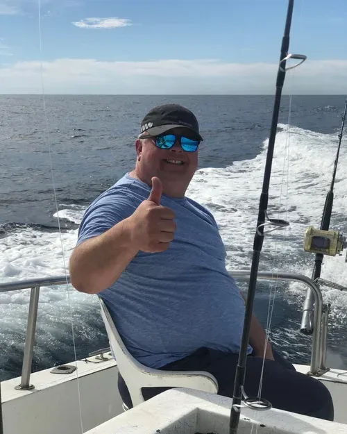 A man on a fishing boat giving a thumbs up.
