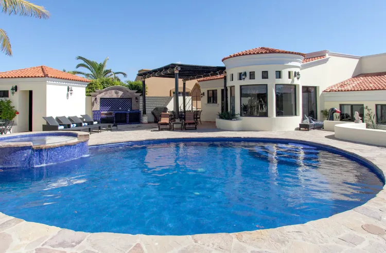 Luxurious villa with a blue swimming pool and palm trees.