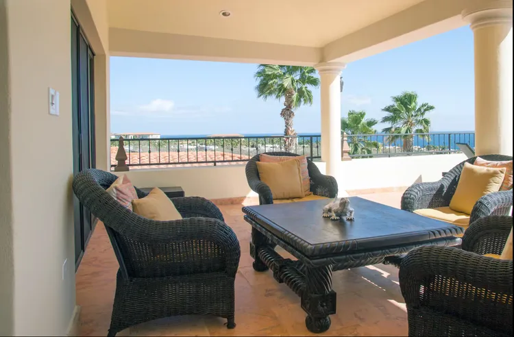 An outdoor seating area with wicker chairs and an ocean view.