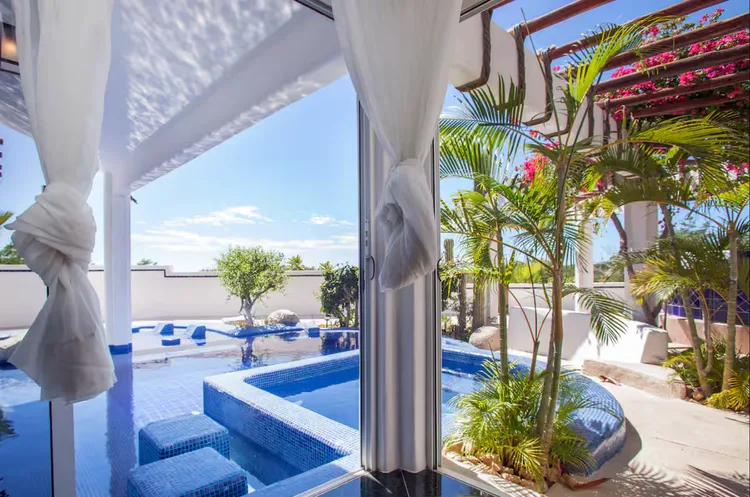A tropical pool area with plants and a blue sky.