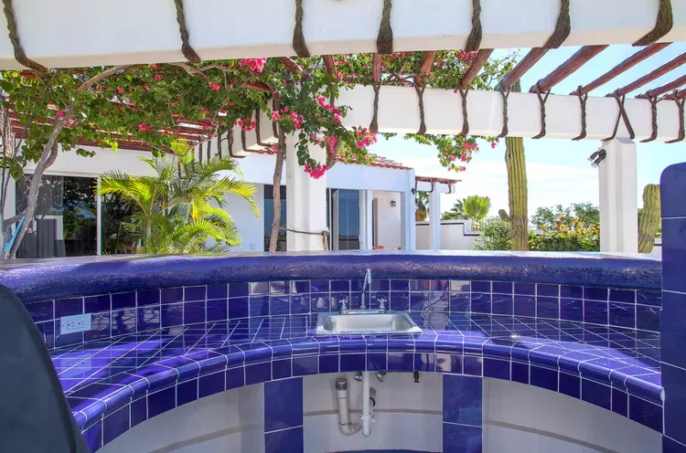 An outdoor kitchen area with blue tiles and tropical plants.