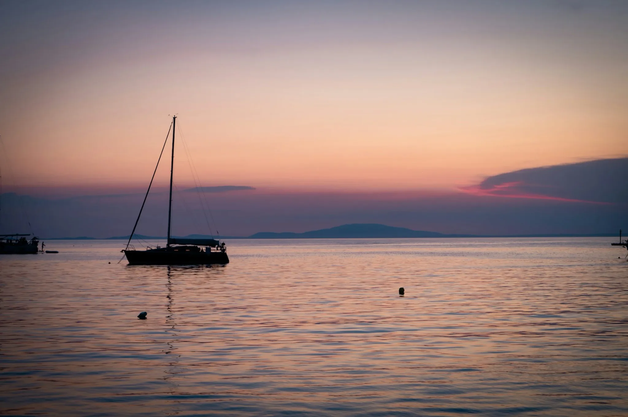 Sailboat at sunset on calm waters.