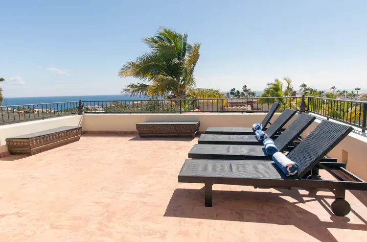 Rooftop terrace with lounge chairs and ocean view.