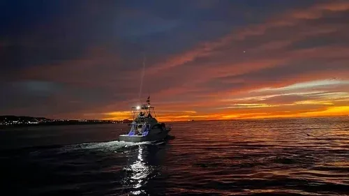 A fishing boat sailing during a colorful sunset.