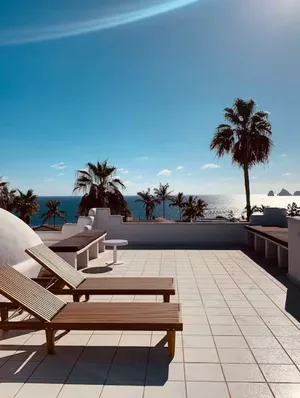 Rooftop terrace with wooden loungers and ocean view.