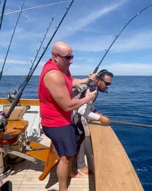 Two men fishing on a boat in the ocean.