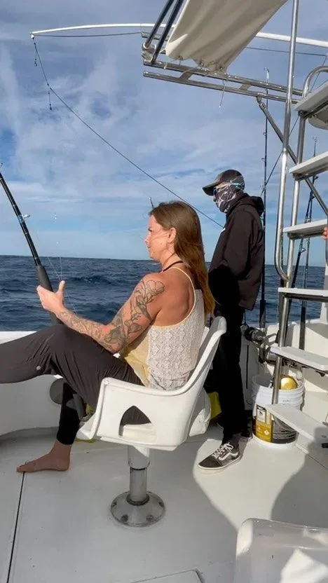 Two people fishing on a boat in the ocean.