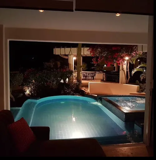 An evening view of a illuminated swimming pool and spa area.