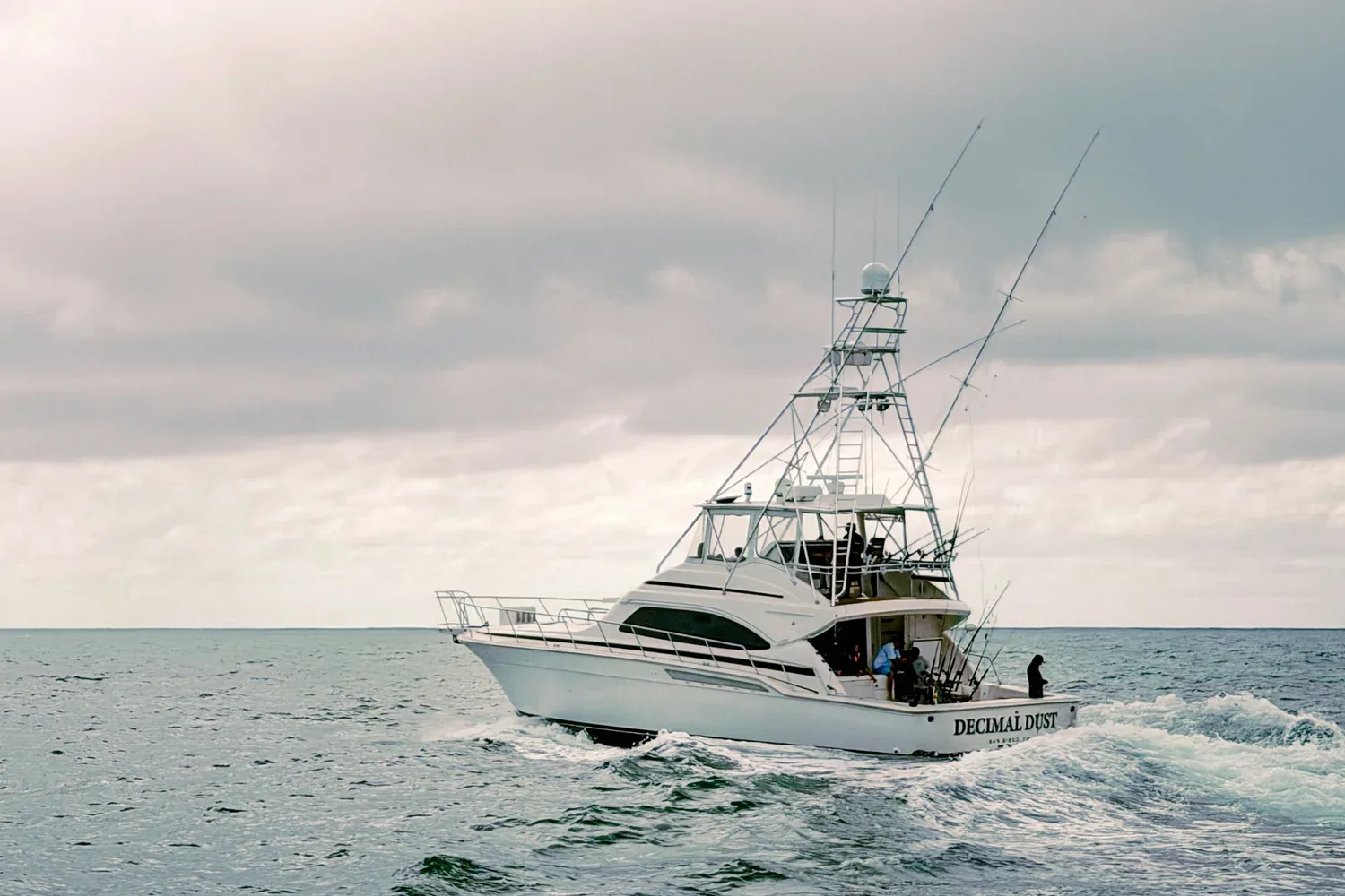 A white fishing boat named 'Decimala Dos' on the ocean.