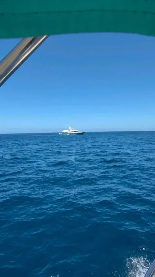 A luxury yacht on a clear blue sea under sunny skies.