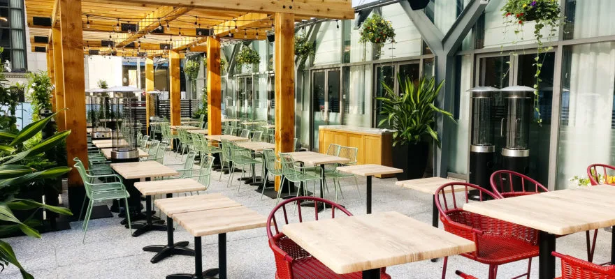 A vibrant outdoor patio with wooden tables and colorful chairs.