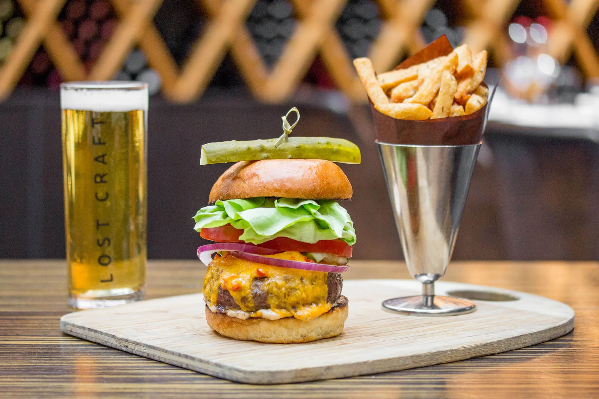 A cheeseburger with fries and a glass of beer.