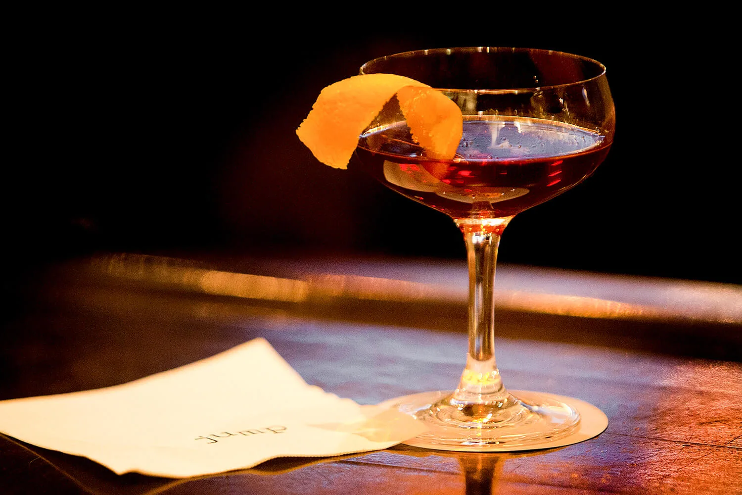A cocktail in a coupe glass with an orange twist garnish.