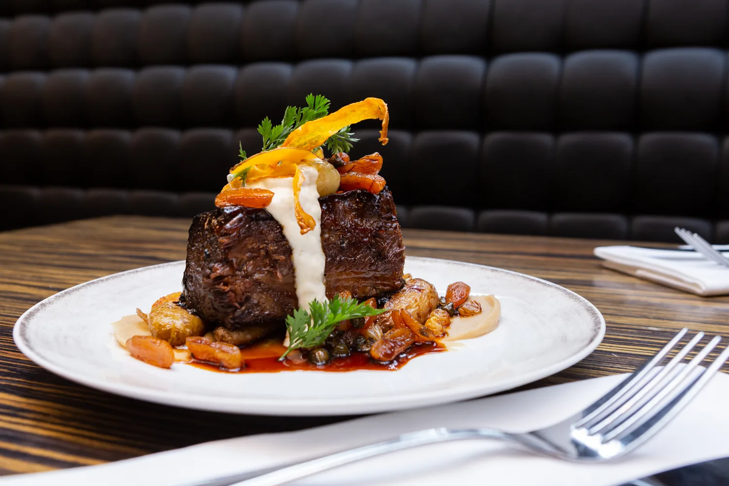 A gourmet beef dish with vegetables on a plate.