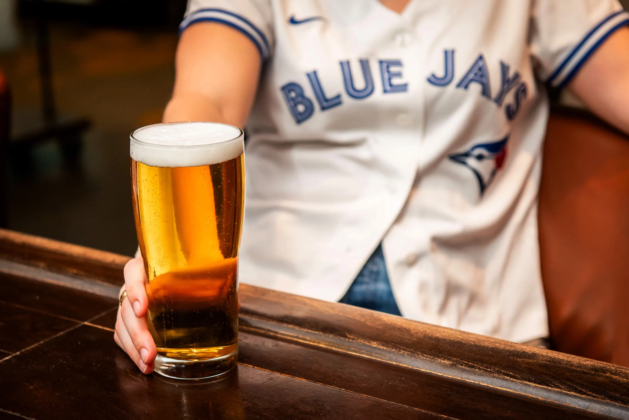 A woman in a jersey holding a pint of beer.