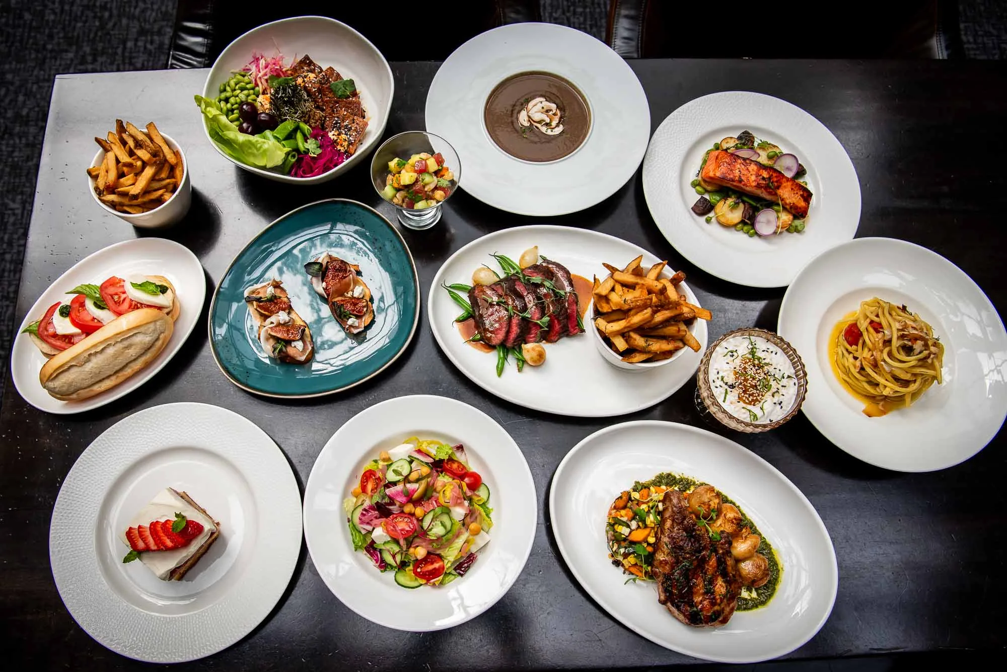 A spread of gourmet dishes on a dark table.