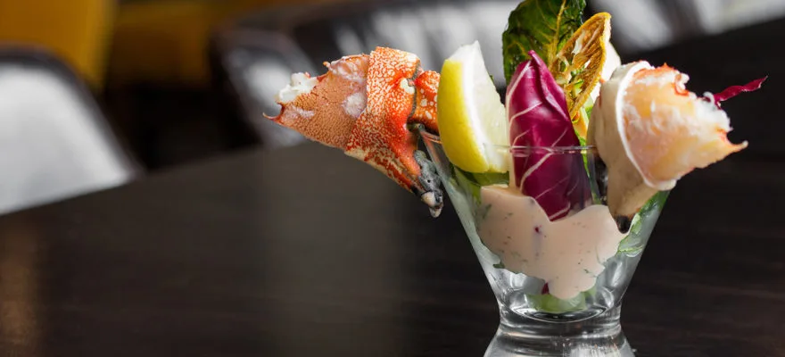 A seafood dish with lobster and colorful vegetables in glass.