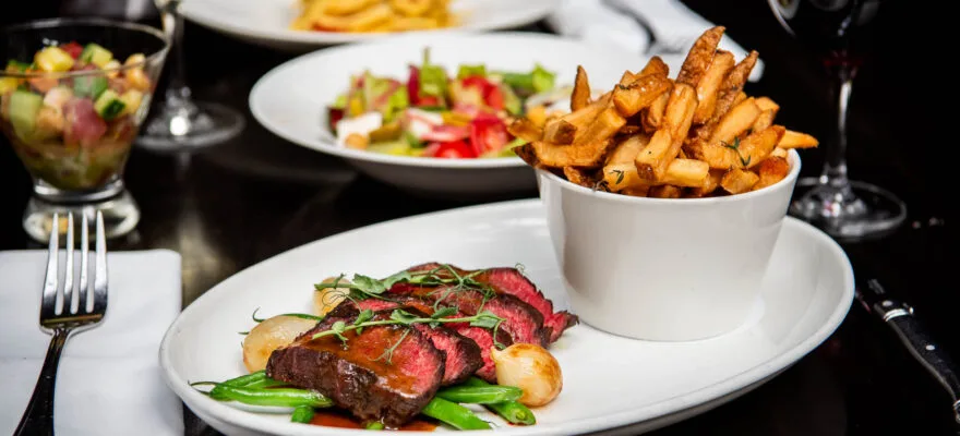 A plate of steak frites with fries and green beans.
