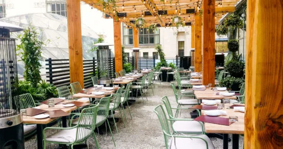 An outdoor dining patio with green chairs and wooden tables.