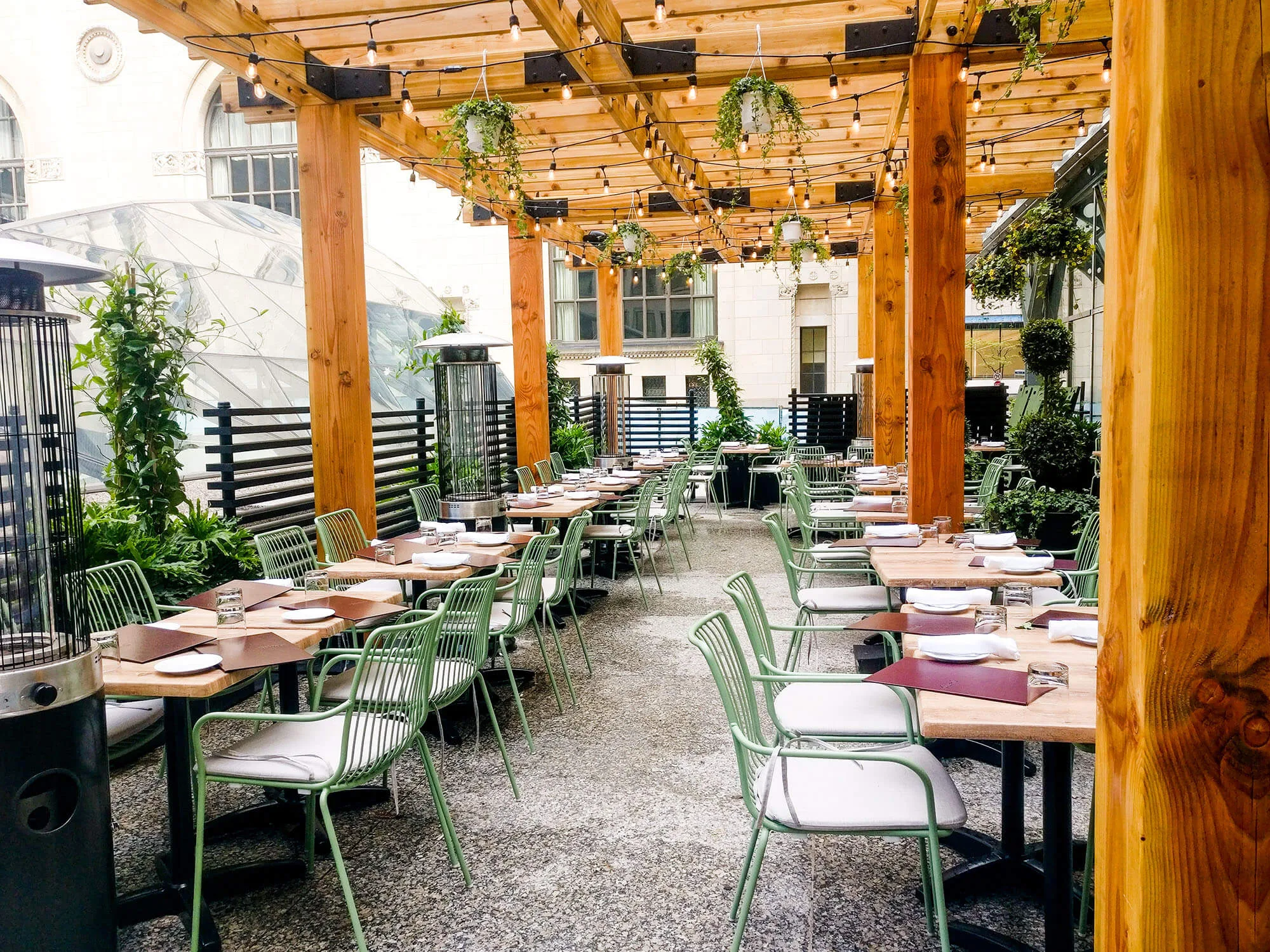 A patio dining area with green chairs and wooden beams.