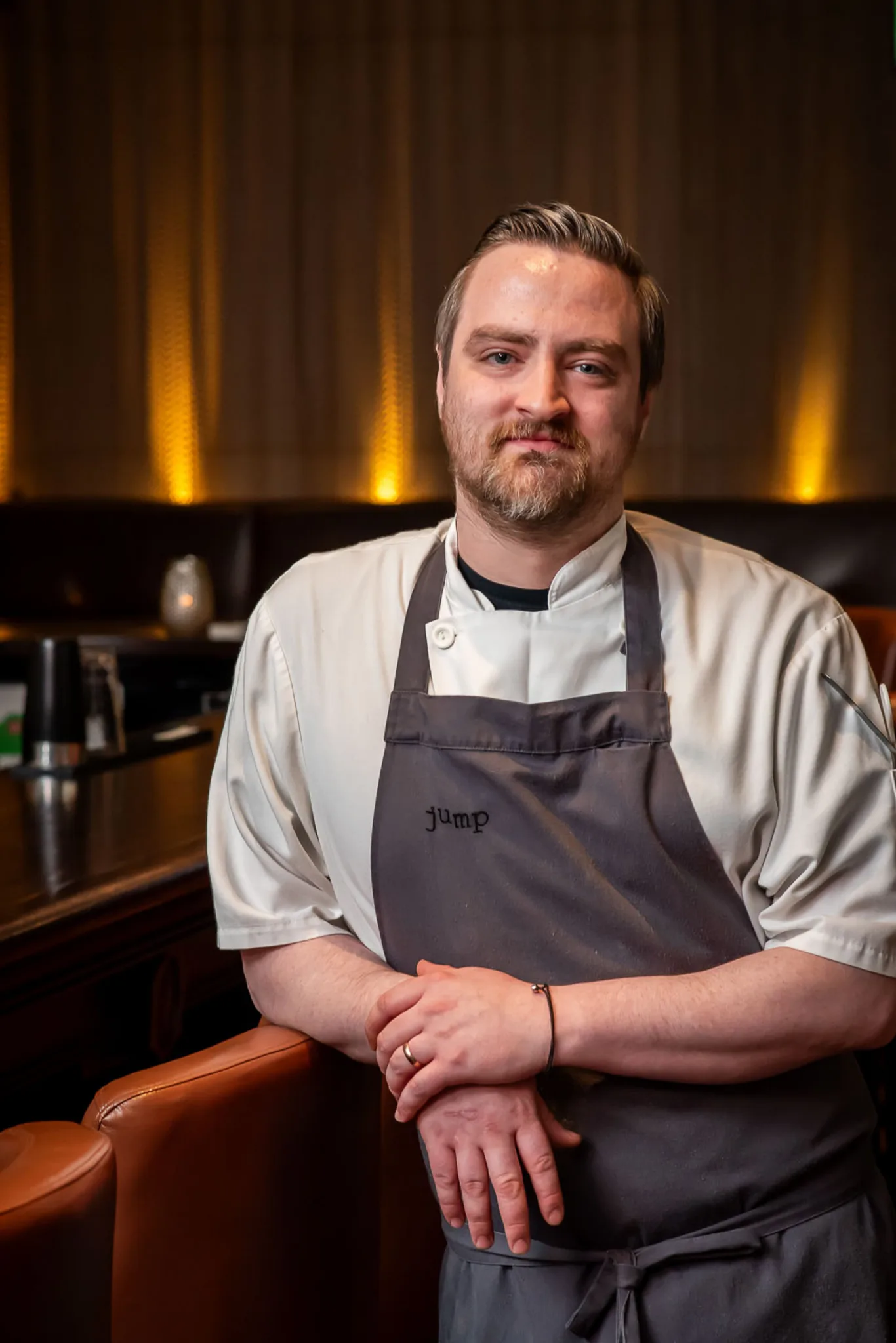 Chef in a gray apron at Jump Restaurant bar.