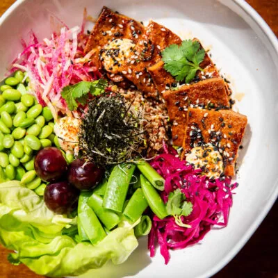 A colorful tofu bowl with various fresh ingredients.