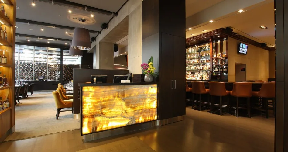 Interior of a modern restaurant with warm lighting and a bar.