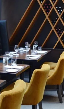 Dining table with yellow chairs and wine display.