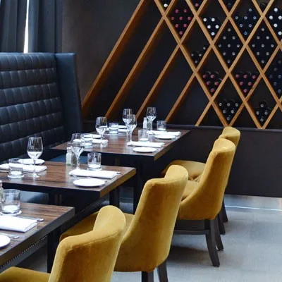 Modern restaurant interior with leather booths and yellow chairs.