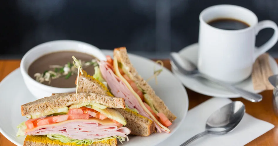Sandwich and soup combo with coffee on a plate.