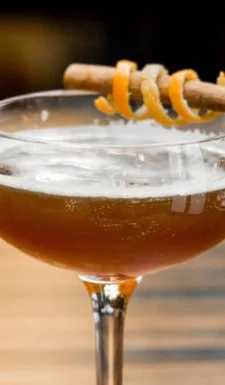 A cocktail garnished with cinnamon and orange peel.