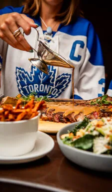 A woman pours sauce over a tomahawk steak at a restaurant.