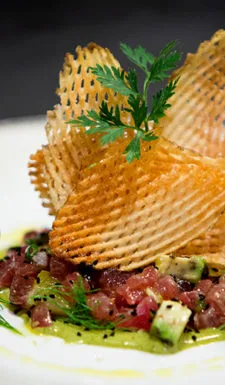 Crispy potato chips on avocado and tuna salad.